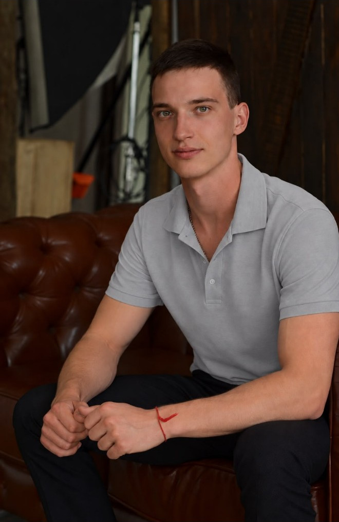 Roman Maliuha im grauen Poloshirt, auf einem braunen Sofa sitzend
